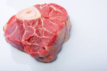 one piece of raw beef meat with the bone in the middle on a white background