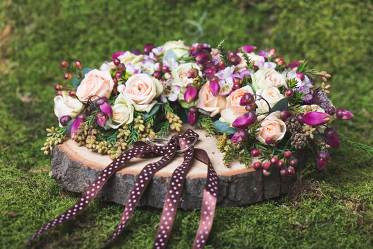Close up image of wedding rings on decorated wooden base. Flower decoration.