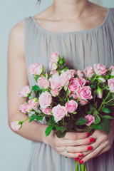 Wedding bouquet of flowers, young bridesmaid holding a bouquet of pink roses. 