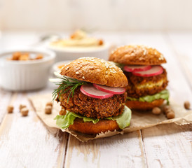 Falafel burger with addition of fresh  radish, onion, dill and Iceberg lettuce on a wooden rustic table. Healthy and delicious  vegetarian dish