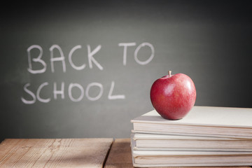 School books with apple on desk 