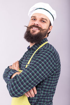 Studio shot of a bearded man with cook hat  holding arms crossed