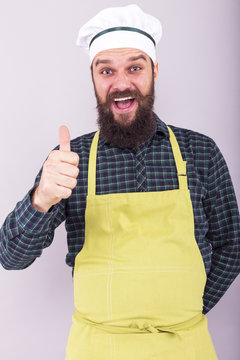 Studio shot of a bearded man with cook hat  showing ok sign