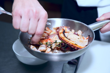 Chef is frying sefood to create delicious dish