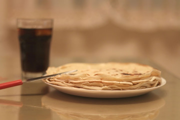 Plate of crepes, with a knife and glass of soda. Selective focus. 