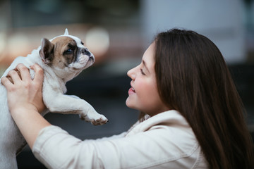 Beautiful teenage girl holding a French bulldog puppy