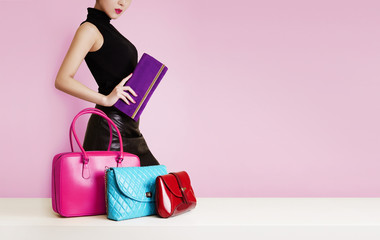 Woman with a  purse passing in front of the colorful bags. Fashion image with copy space.  - obrazy, fototapety, plakaty