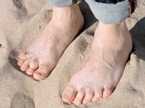 Male bare feet on sand