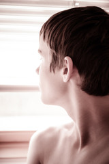 Thoughtful young boy staring out of a window
