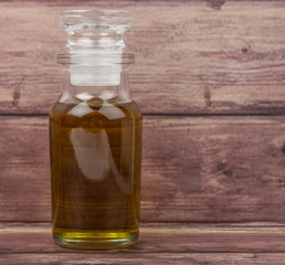 Fototapeta na wymiar Avocado oil in glass vial over wooden background