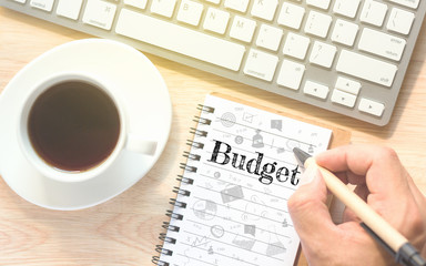 Hand writing on book message Budget. A keyboard and a glass coffee table.Vintage tone.