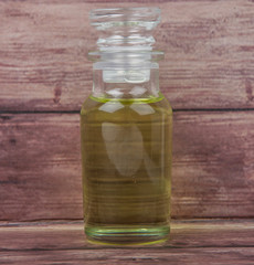 Grape seed oil in glass vial over wooden background