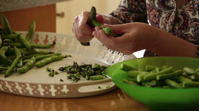 Houswife prepare pods ( broad bean ) for dinner at home