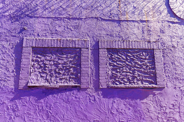 violette Fassade mit zugemauerten Fenstern