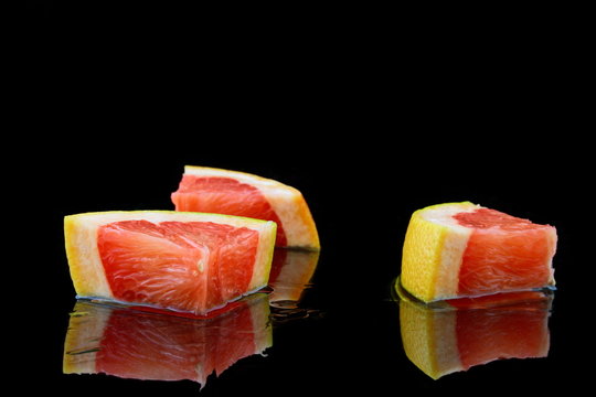 drei st&uuml;ckchen grapefruit auf schwarzen hintergrund