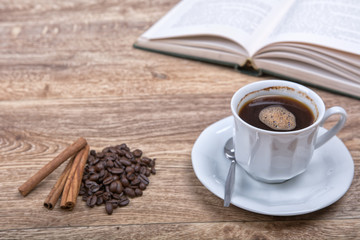 A cup of coffee with a book on a wooden background