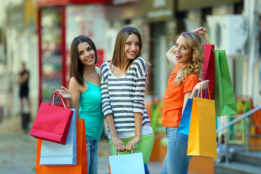 Beautiful young women with shopping bags on city street