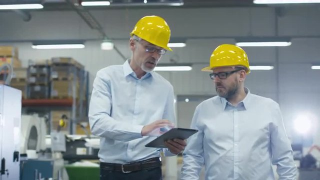 Two employees are walking with tablet computer at logistics center warehouse. Shot on RED Cinema Camera.