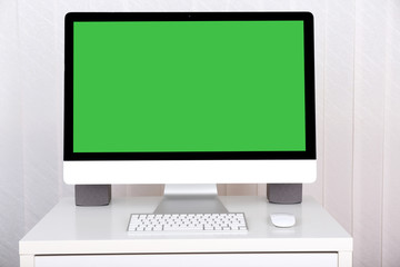 Modern computer with green screen, on table