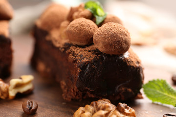 A piece of chocolate cake with walnut and mint on the table, close-up