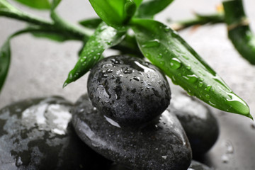 Hot spa stones with bamboo on grey background, close-up