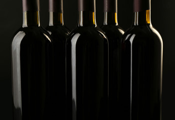 Wine bottles in a row on black  background, close up
