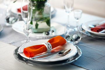 Served table with orange napkin in restaurant, closeup