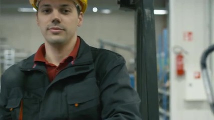 Portrait of a warehouse worker driving a forklift truck. Shot on RED Cinema Camera.