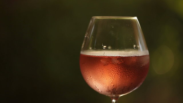 Pouring rose wine into the icy glass with blurry and bokeh background