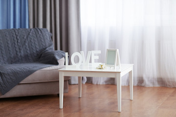 Sofa and little table with home decor in the room in front of the window with curtains