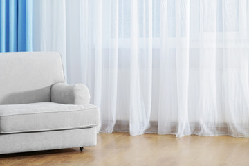 Sofa in the room in front of the window with curtains