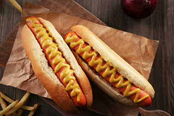 Hot dogs with onions and fried potatoes on wooden background