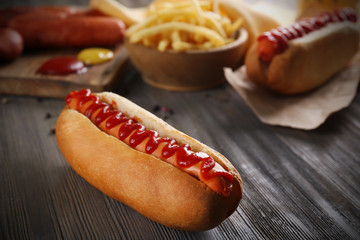 Hot dog with fried potatoes and fresh sausages on wooden background
