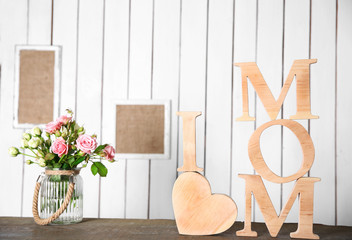 Obraz na płótnie Canvas I love mom inscription of wooden letters with heart and flowers on white wall background
