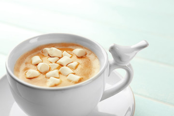 Cup of hot cacao with marshmallow on blue table