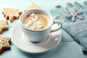 Cup of hot cacao with marshmallow, cookies and warm gloves on blue table