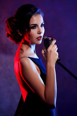 Beautiful brunette woman singing on purple background
