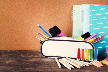 Pencil case with various stationery on old  wooden table