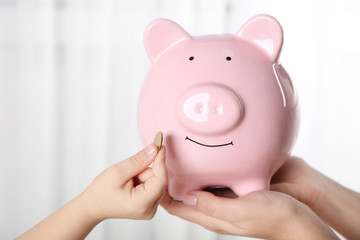 Savings concept. Piggy bank in parent and child hands