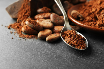 Bowl with aromatic cocoa beans and chocolate on grey background, close up