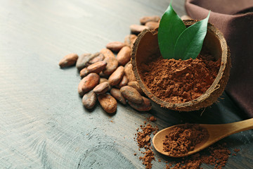 Bowl with aromatic cocoa powder and green leaf on wooden background, close up