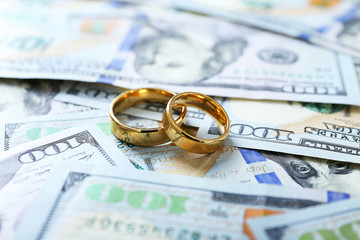 Wedding rings on money background, close up