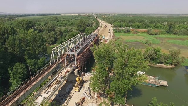 Aerial view on workers with heavy machines working on bridge railway reconstruction.
