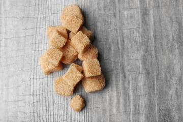 Pile of brown sugar cubes on wooden background