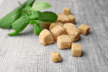 Pile of brown sugar cubes and stevia  on grey wooden background