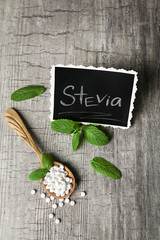 Analogue of sugar cubes and stevia  on grey wooden background