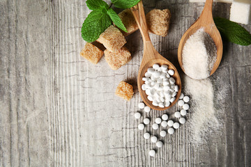 Pile of brown sugar cubes and stevia  on grey wooden background