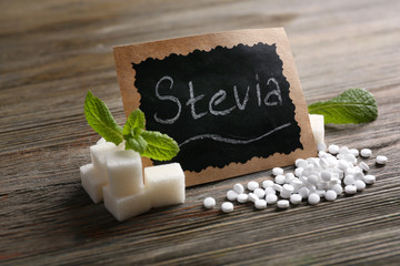 Word STEVIA written on black board and sugar on wooden background