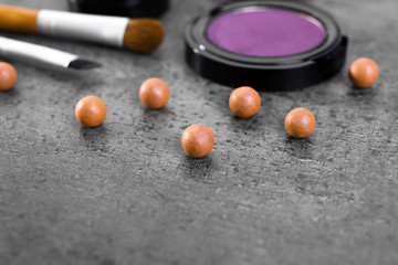 Make-up brush, eye-shadow and blusher balls, on grey background