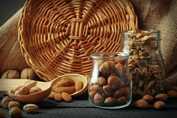 Mix of nuts in the glass jars and wooden spoon, on the table